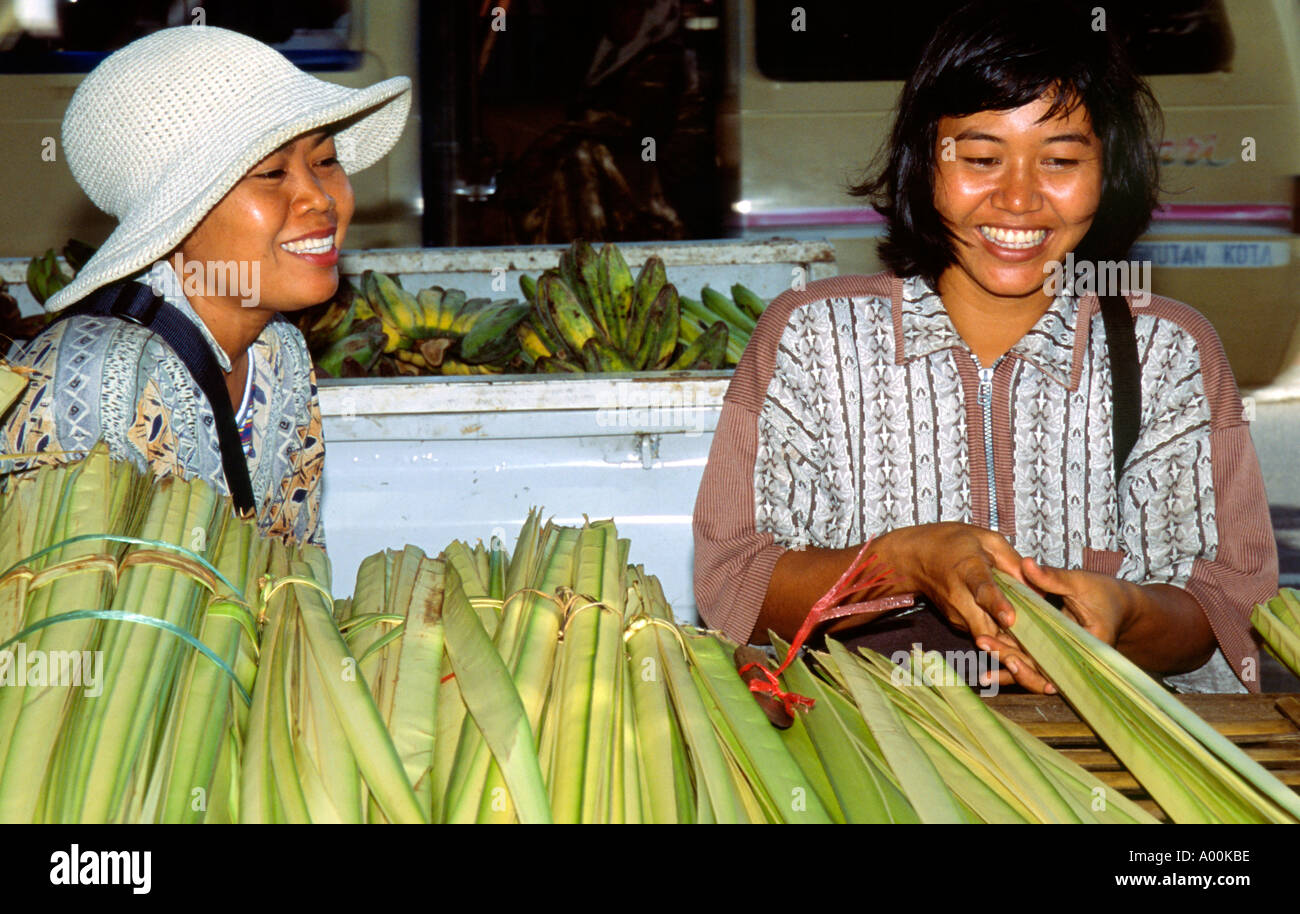 einheimische Frauen mit großen Bündel von Schilf zum Verkauf Lachen als Dachmaterial in der Nähe von Kuta Bali Indonesien Stockfoto