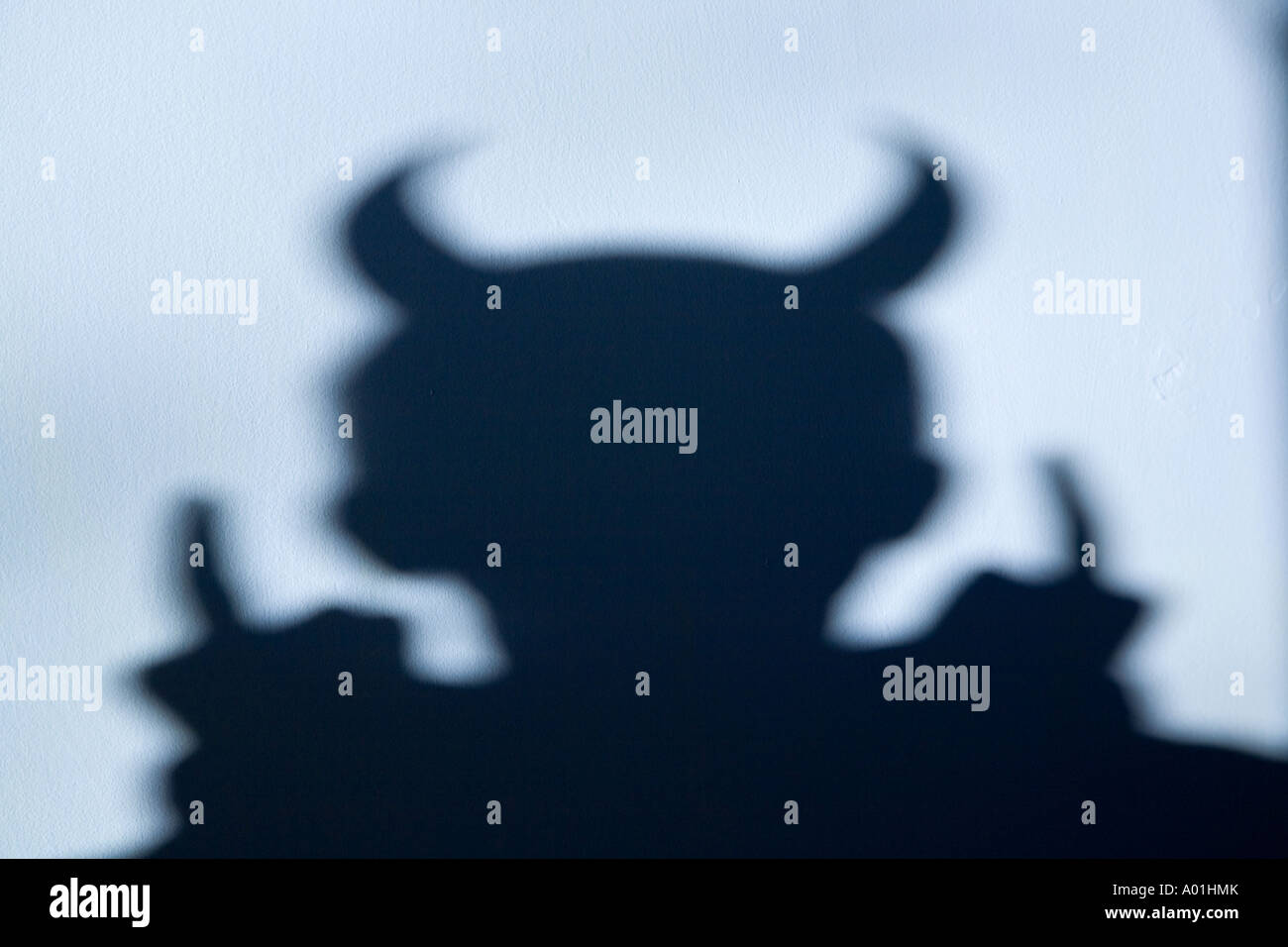 Schatten eines Teufels mit Hörnern auf leichte blaue Wand Stockfoto