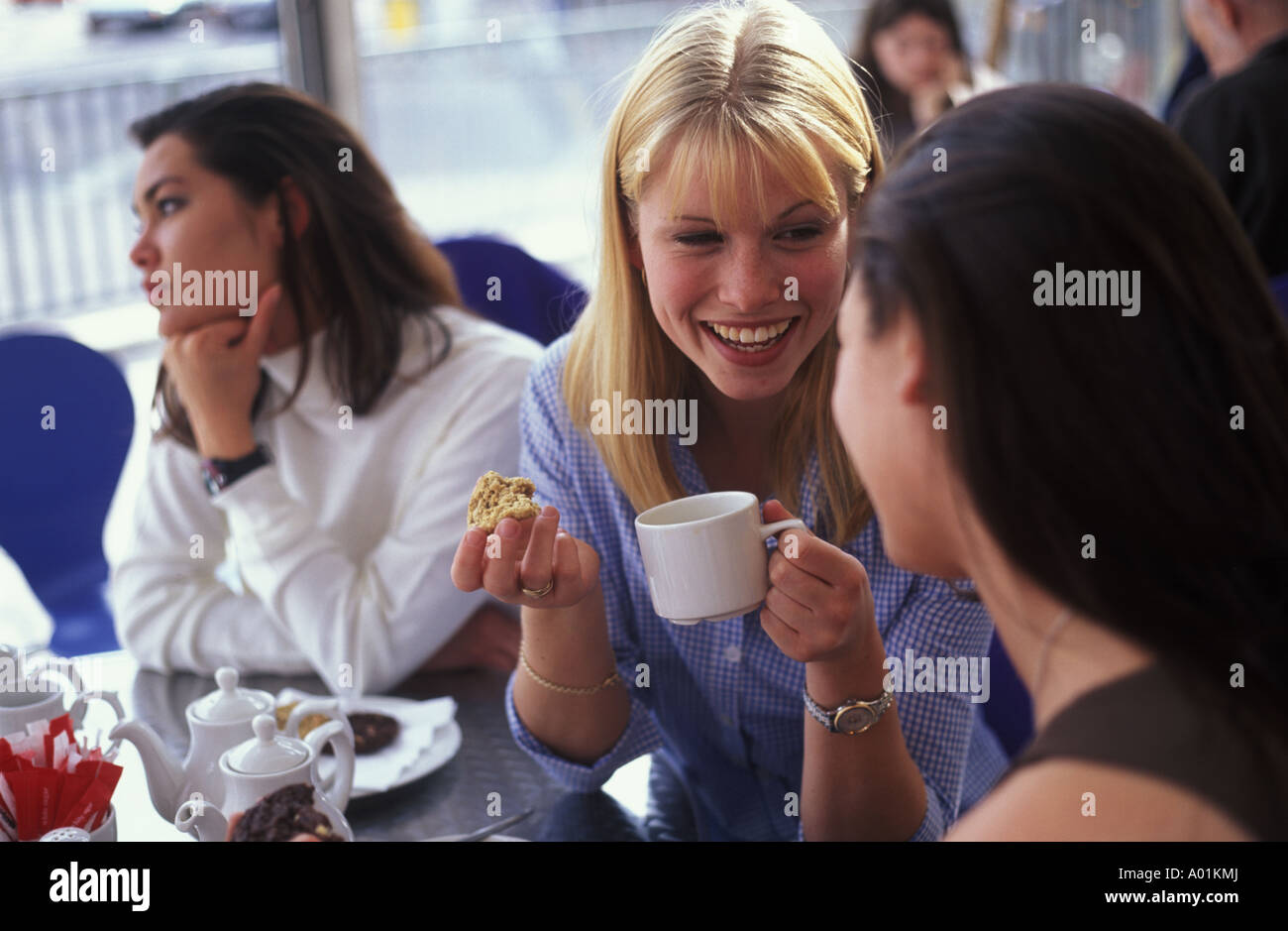 junge Frauen plaudern in einem Café, während ein Freund traurig und allein gelassen sieht Stockfoto