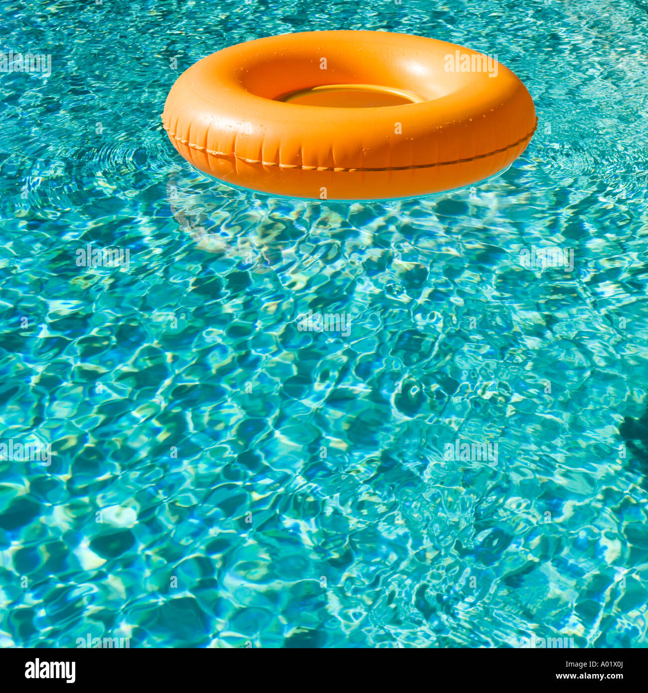Orange aufblasbaren Ring schwebt in einem blauen Swimmingpool wirft einen Schatten Stockfoto