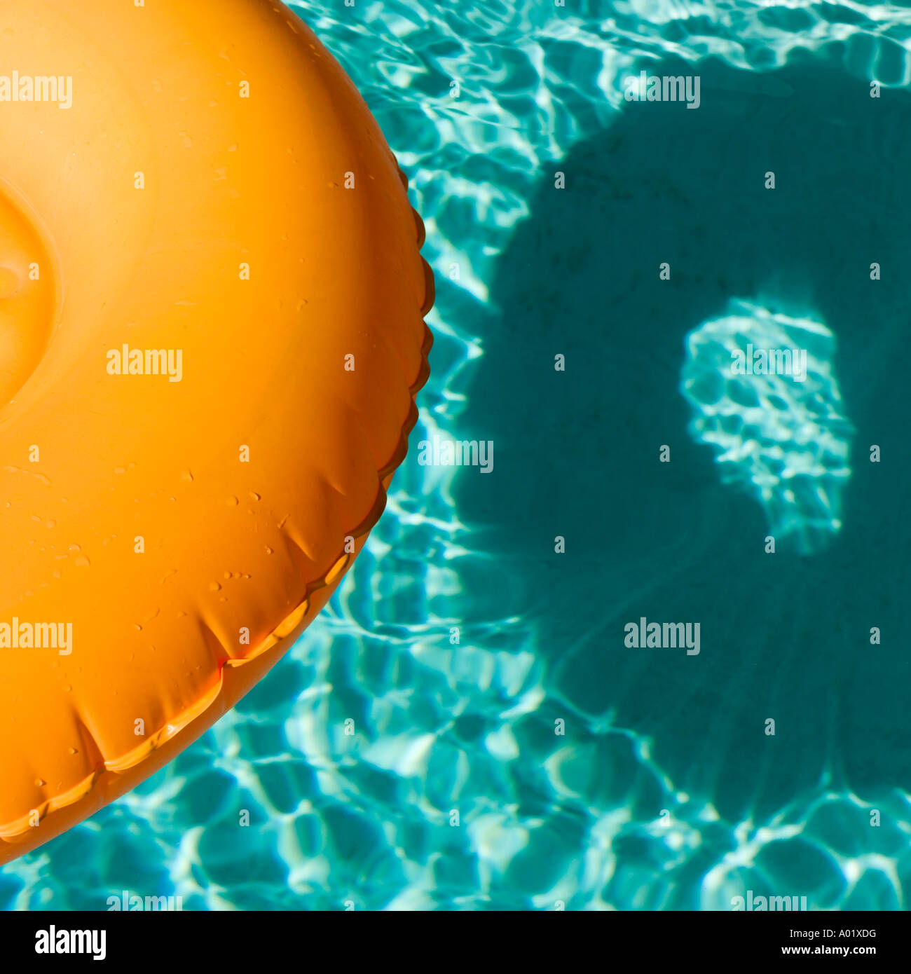 Orange aufblasbaren Ring schwebt in einem blauen Swimmingpool wirft einen Schatten Stockfoto