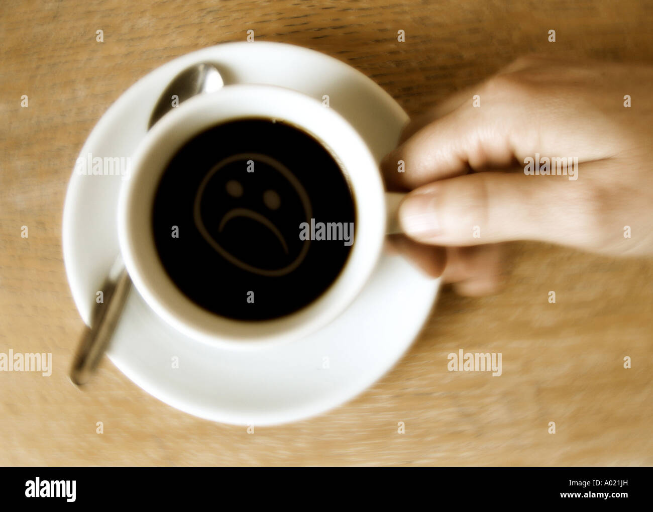 Draufsicht auf der Hand, die eine Kaffeetasse mit traurigen Symbol innerhalb Stockfoto