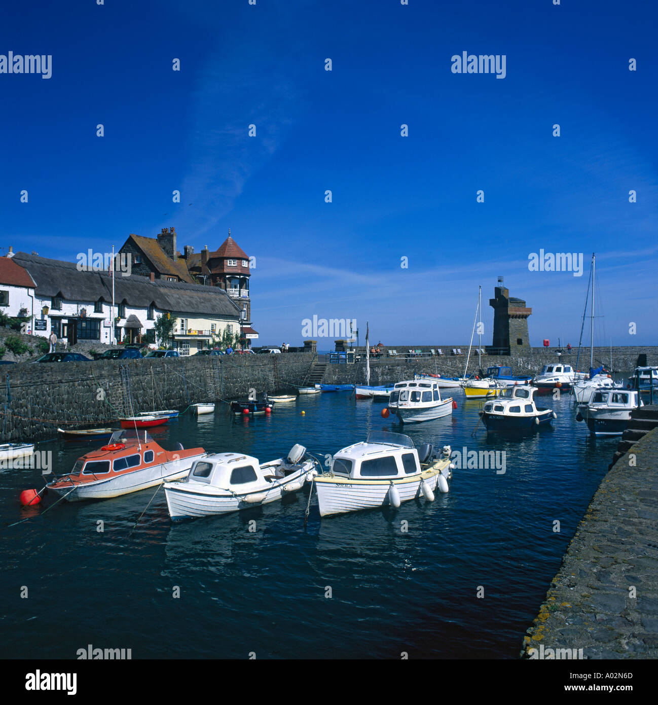 Sommer Blick auf kleine Boote vor Anker im Hafen von Lynmouth mit ziemlich alten strohgedeckten Hütten über North Devon England Stockfoto