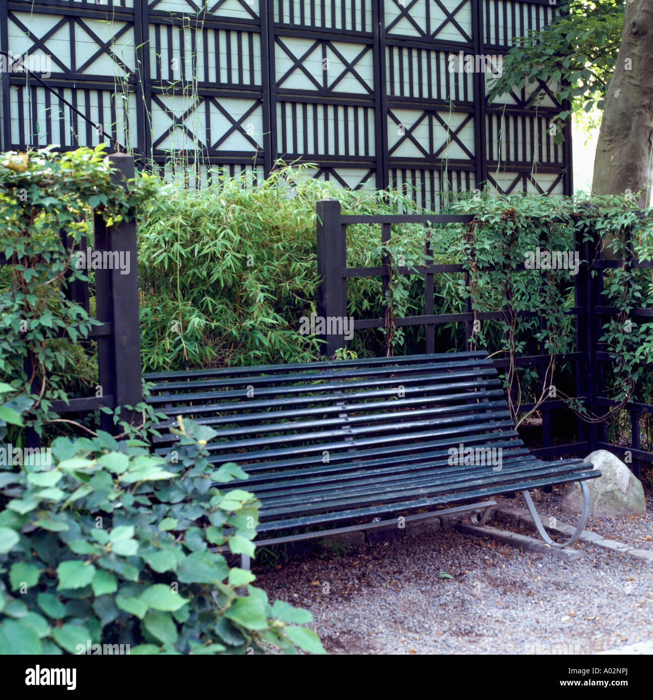 Schwarze Sitzbank gegen Zaun und Arundinaria wartungsarme Garten Stockfoto