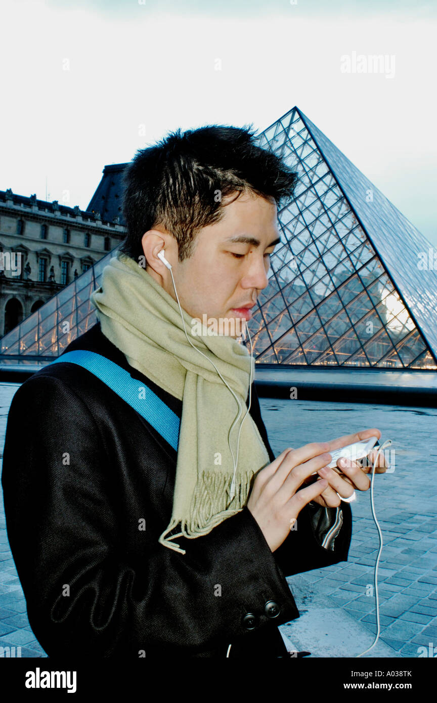 Paris Frankreich, Portrait junger asiatischer Mann, der mir ZUGEHÖRT, Musikspieler, mit Kopfhörern bei Dämmerung, der Pyramide des Louvre Stockfoto