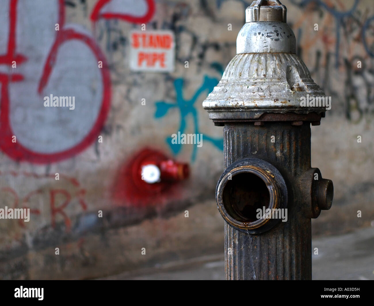 Alten, offenen Hydranten vor einer Graffiti-bedeckten Wand in der Nähe von Harlem in New York City. Stockfoto
