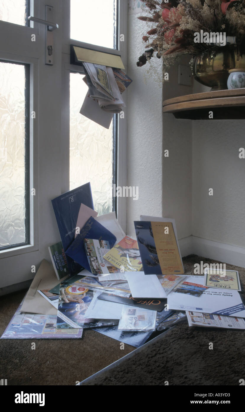 Vordertür Matte & große Ansammlung von Junk-Mail-Briefe Rundschreiben & Urlaub Broschüren im Stapel unter Briefkasten, während weg von zu Hause Essex England Großbritannien Stockfoto