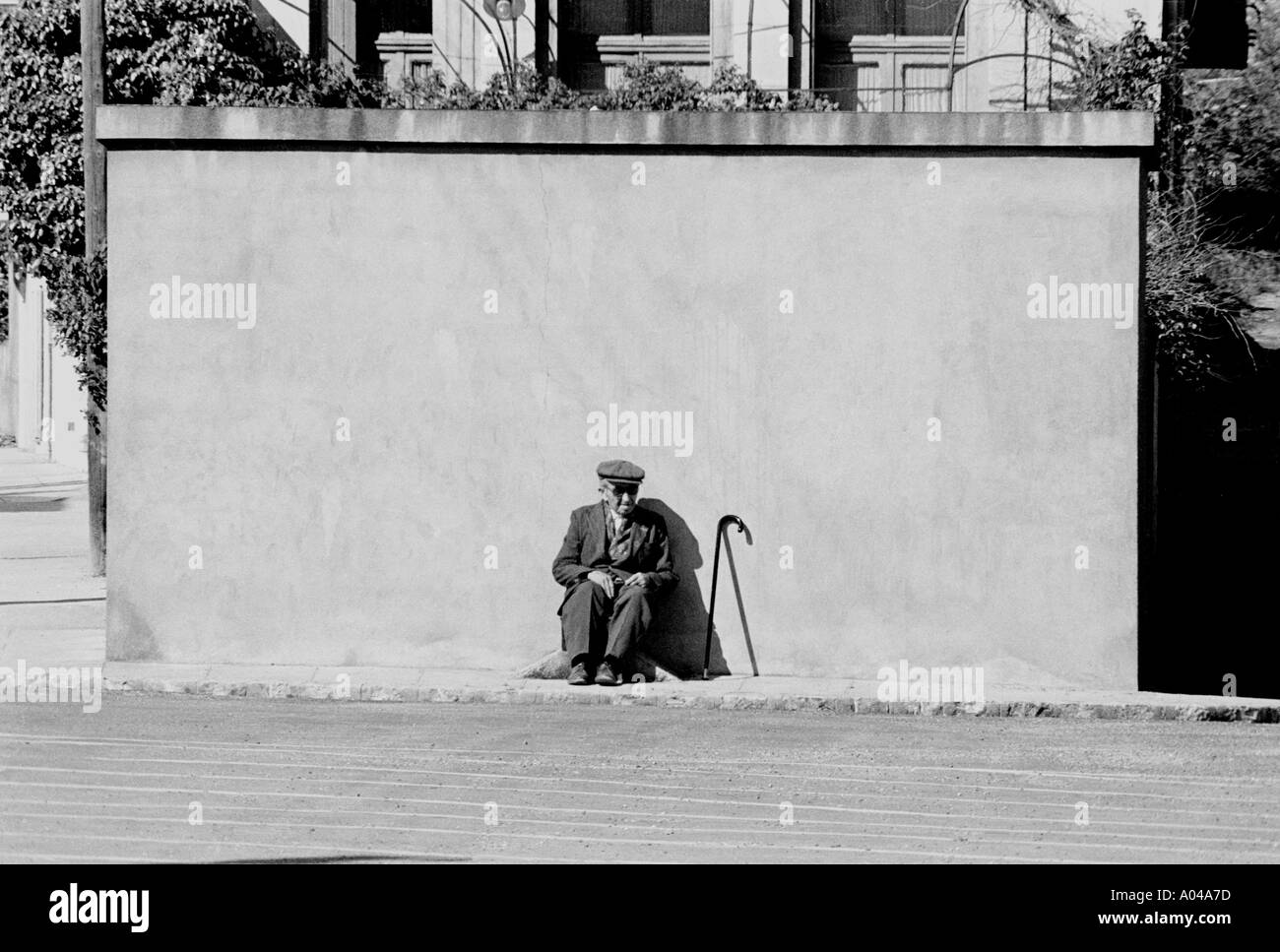 Ein alter Mann sitzt in der Sonne an einer Mauer in der französischen Stadt Lyon. Stockfoto