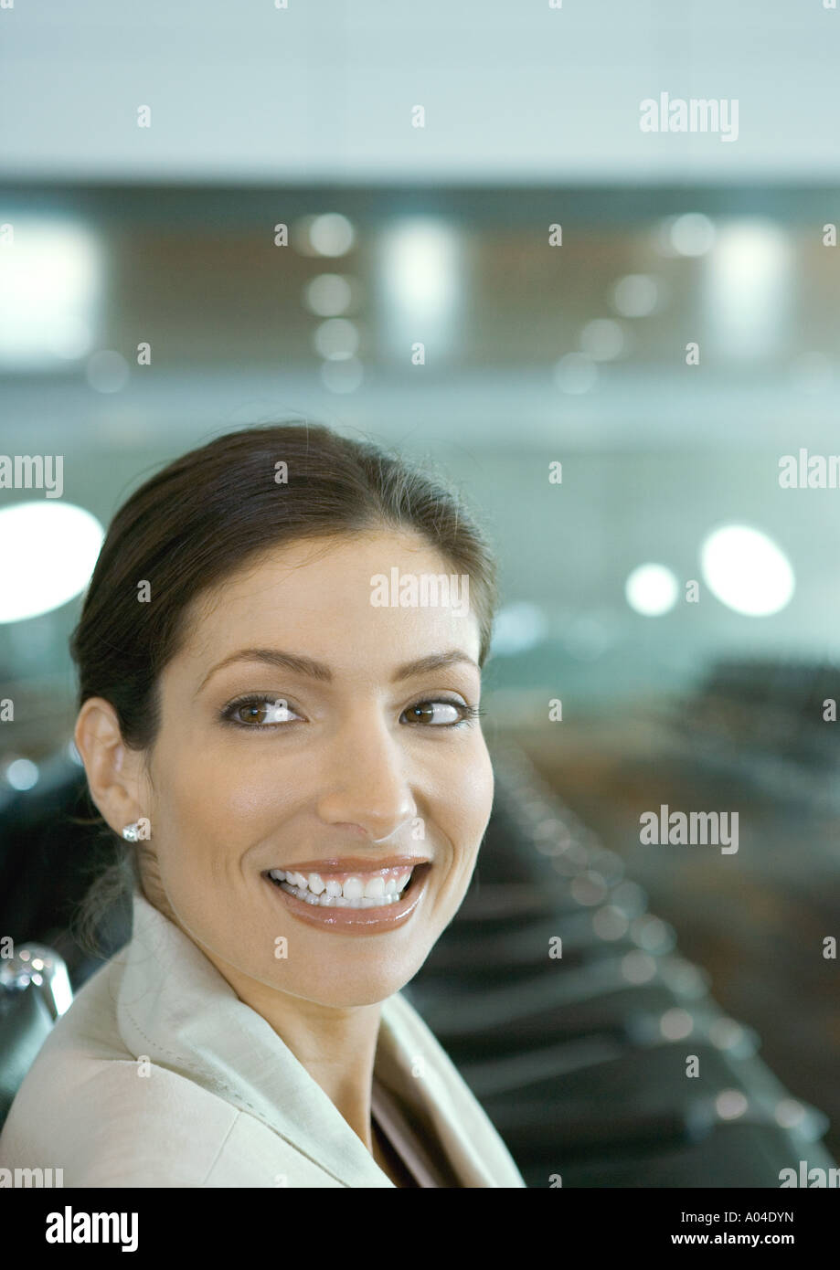 Frau in der Flughafen-Lounge, lächelnd über die Schulter Stockfoto
