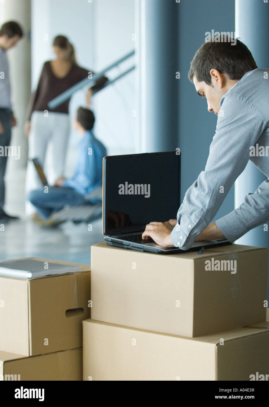 Geschäftsmann mit Laptop auf Karton Stockfoto