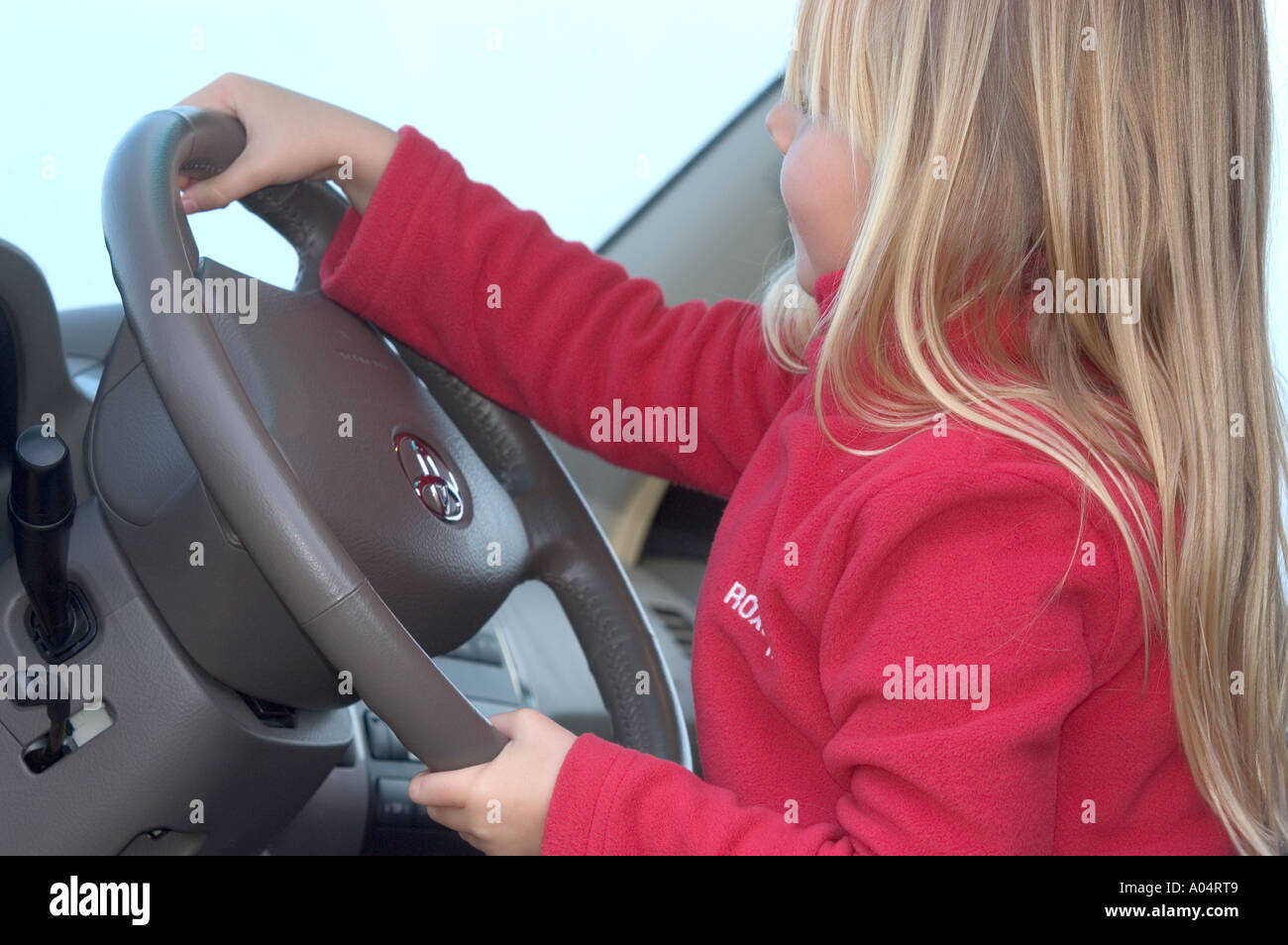 Kleines Blondes Mädchen Saß am Steuer Vom Auto Und Simulation Lenk