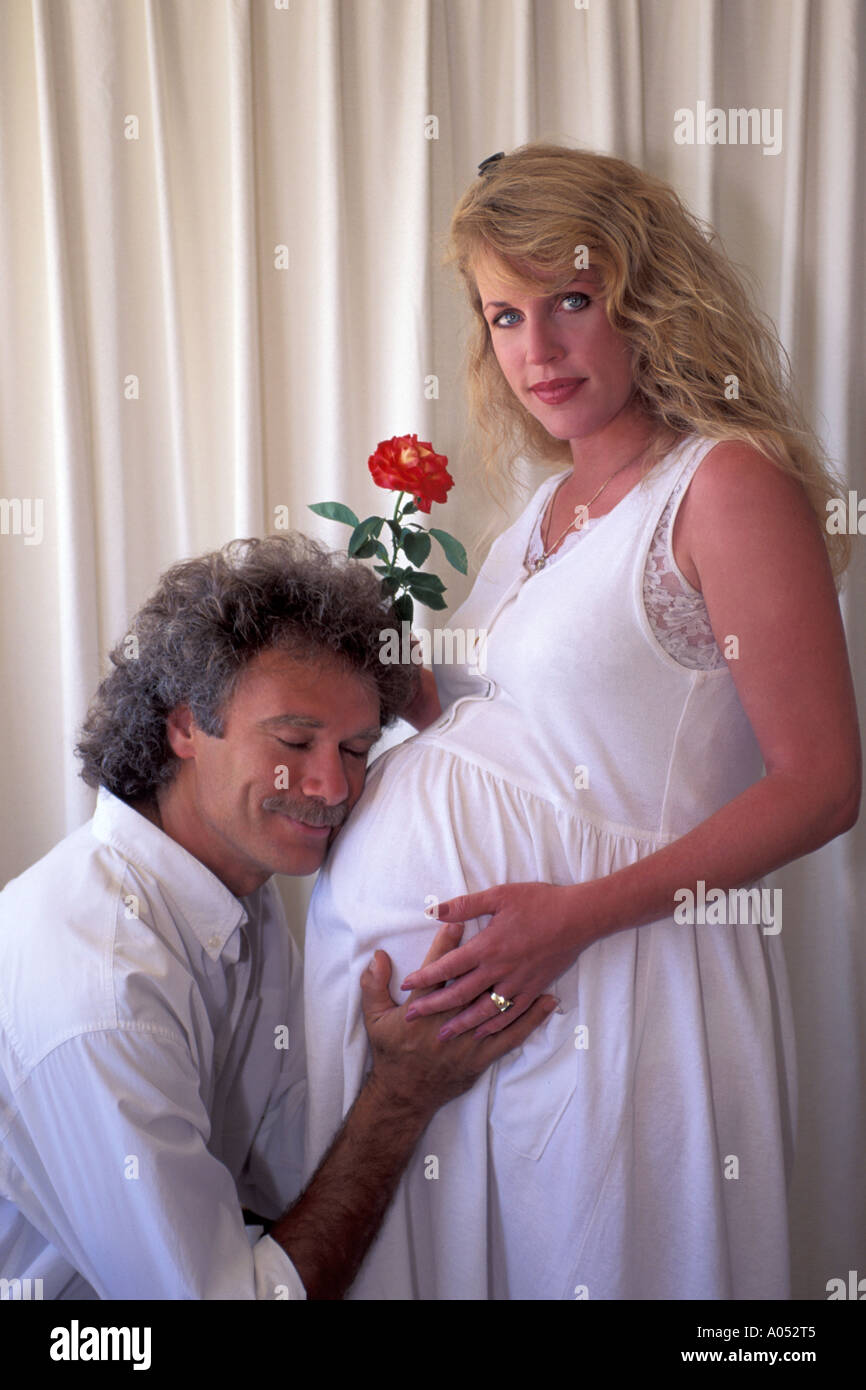 glücklicher Ehemann mit Lächeln auf seinem Gesicht halten Wifes schwangeren Bauch mit dem Ausdruck seiner Liebe für Eltern Stockfoto