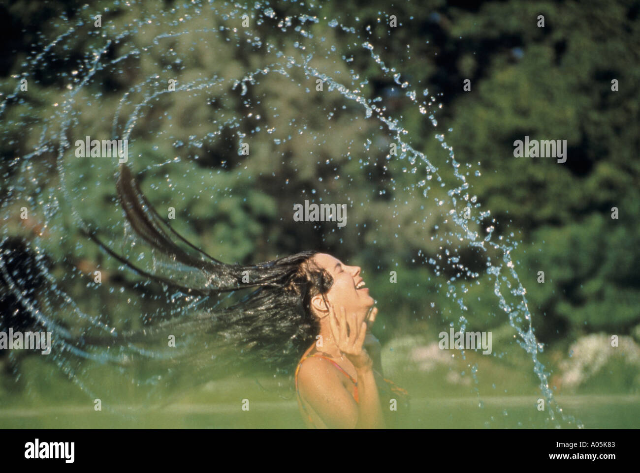 Frau ergibt sich aus dem Pool mit ihr nasses Haar Spritzwasser überall Stockfoto