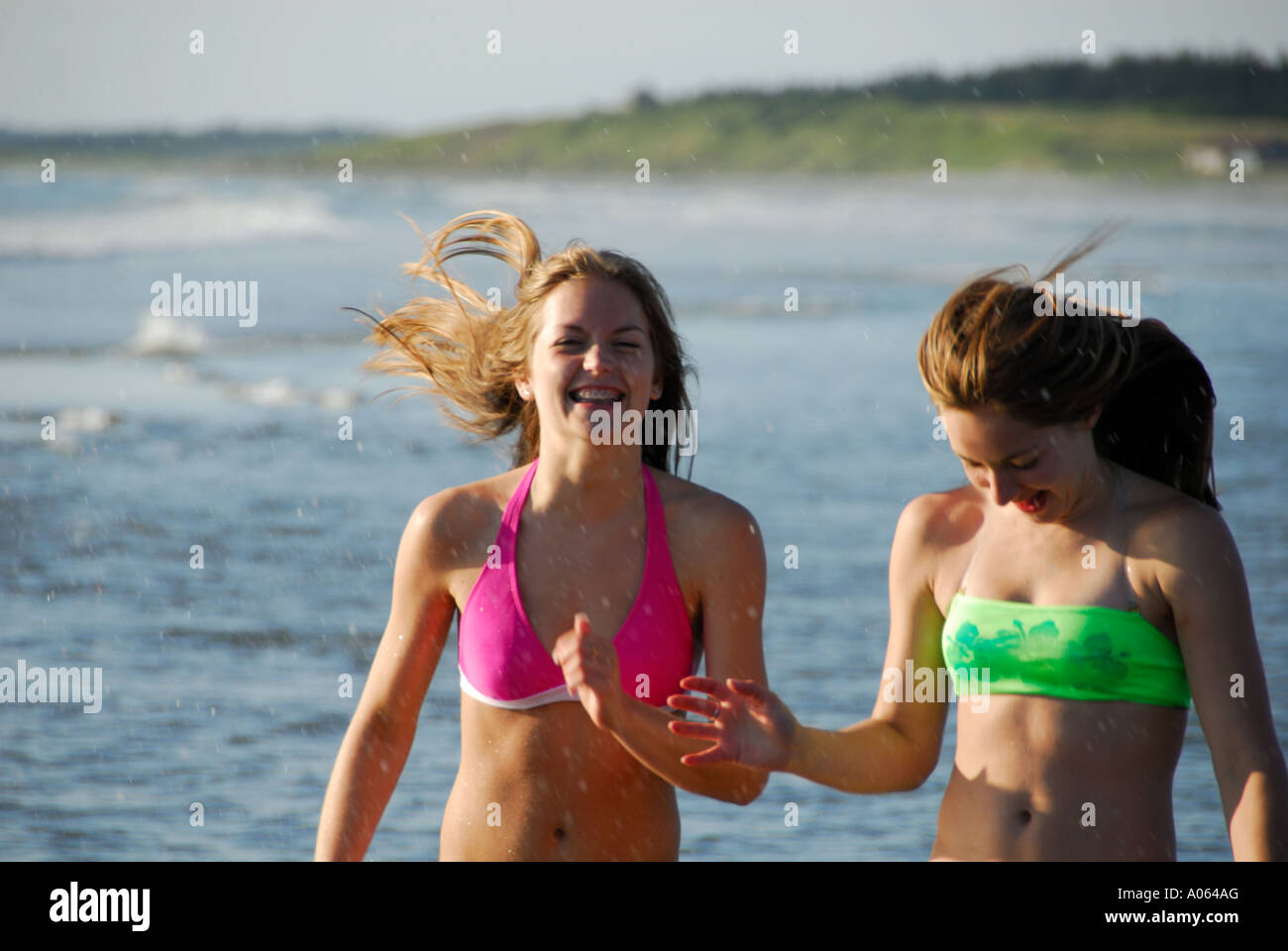 zwei Mädchen im Teenageralter zusammen am Strand laufen Stockfoto