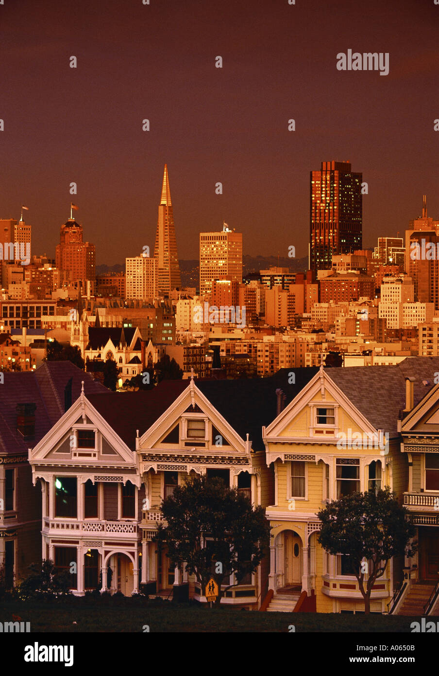 Viktorianische Häuser auf Steiner Street Alamo Square bei Sonnenuntergang mit Skyline über San Francisco Kalifornien, USA Stockfoto