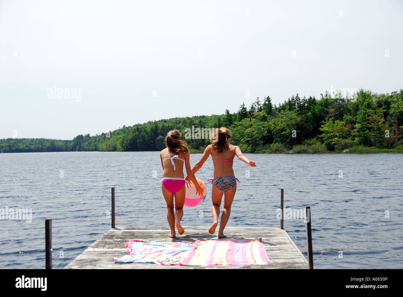 Mädchen im Teenageralter abspringen docken an See Stockfoto