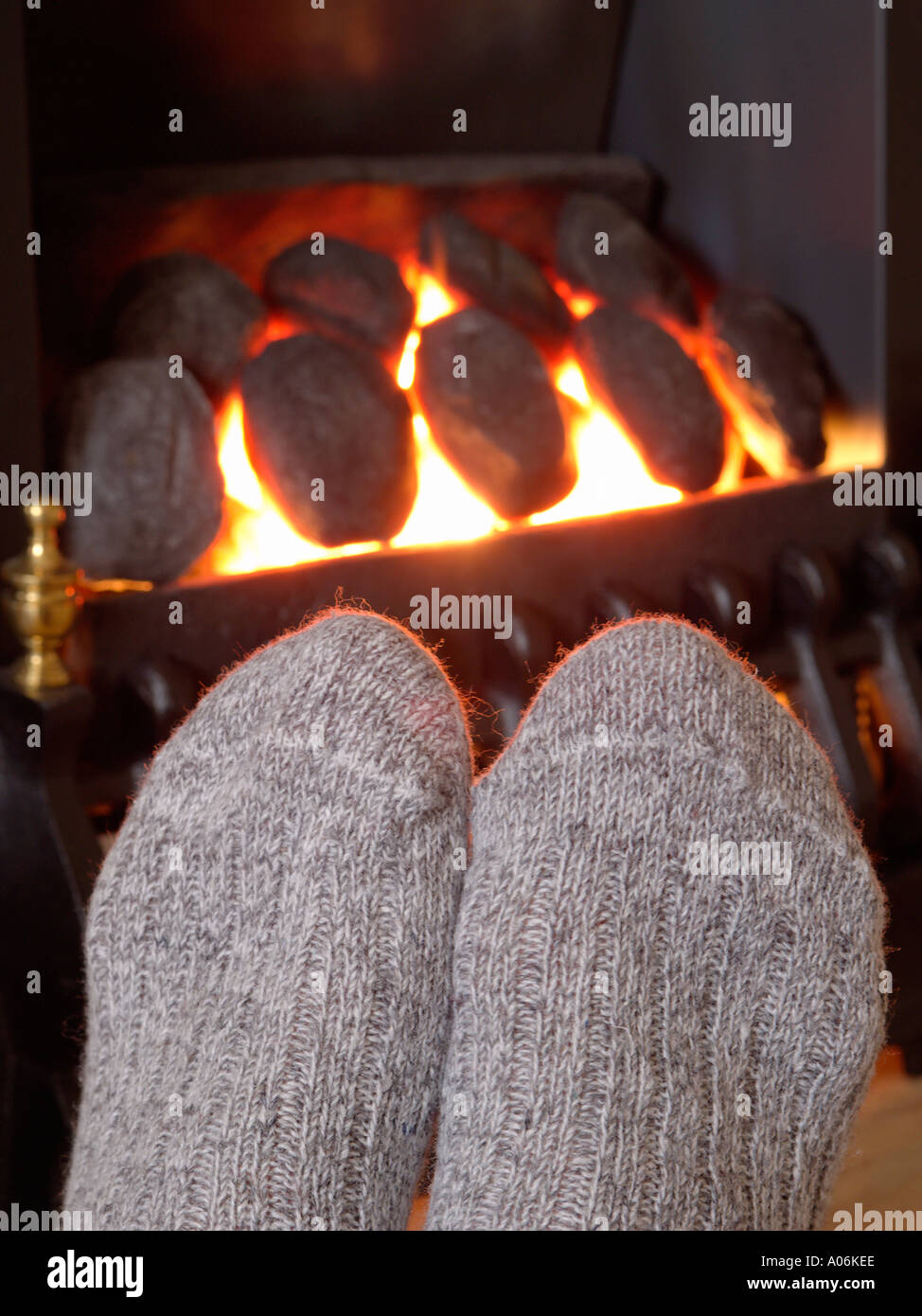 WARME FÜSSE in kuscheligen wolligen Socken, die sich vor einem echten Flammenfeuer im Wohnzimmer in einem Kamin erwärmen. England Großbritannien Stockfoto