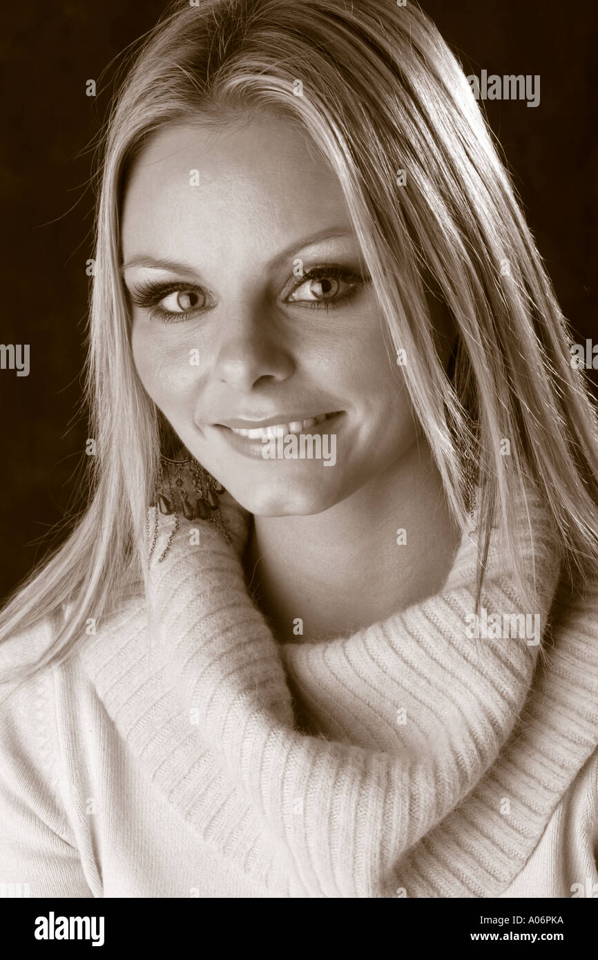 Sepia Porträt von einem lächelnden blonden Mädchen trägt einen Pullover Stockfoto