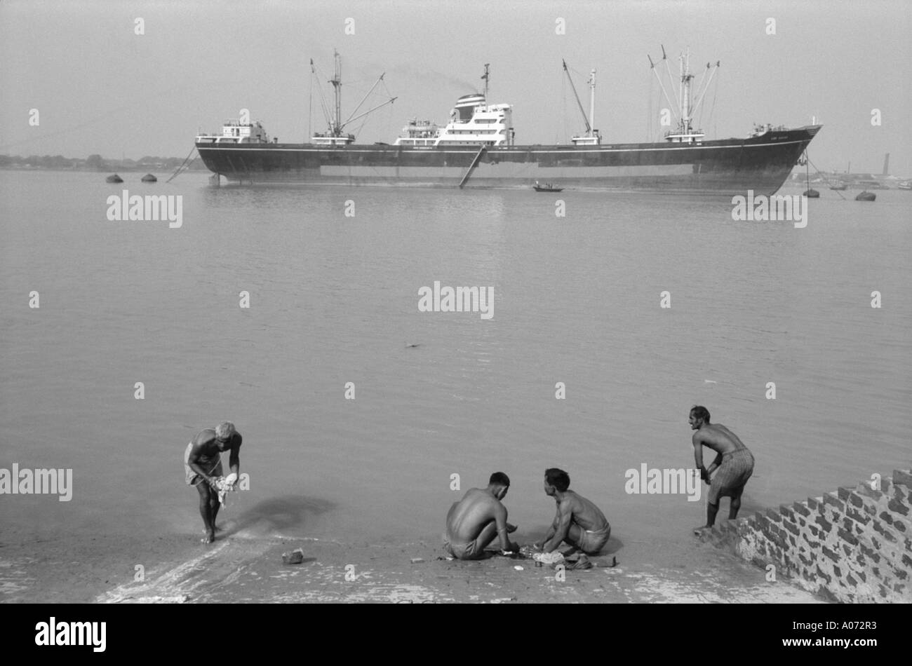 Vier Männer Wäsche waschen und Schiff in Hoogly river Kalkutta Kalkutta Westbengalen, Indien Stockfoto