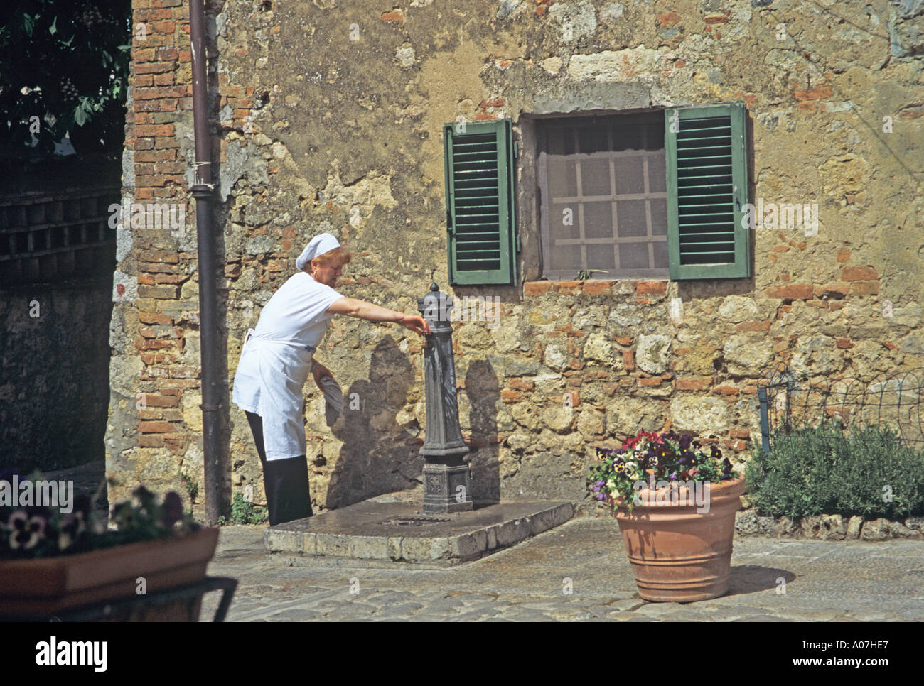MONTERIGGIONI Toskana Italien Europa kann Frau mit der Wasserpumpe auf dem Hauptplatz von dieser historischen Festungsstadt Stockfoto