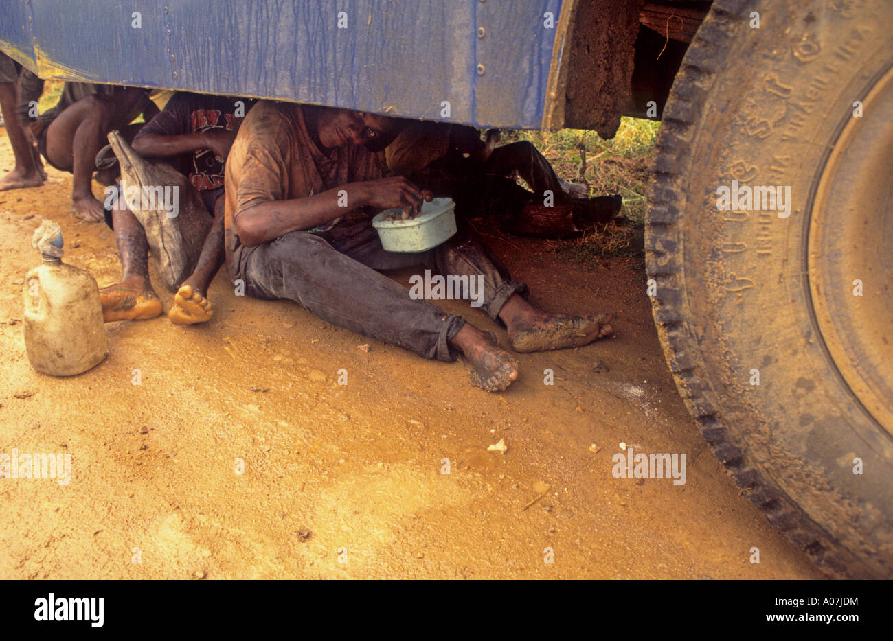 Moderne Sklaverei. Zuckerrohr-Fräser beim Mittagessen unter dem Bus um sich zu schützen vor Regen, Brasilien Stockfoto