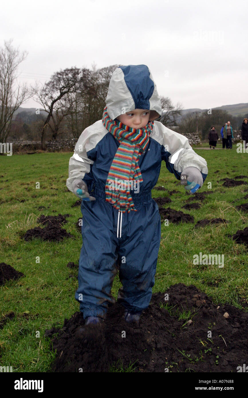 Vertikale Nahaufnahme eines kleinen Jungen spielen im Schlamm eine alles in einem wasserdichten Anzug tragen. Stockfoto