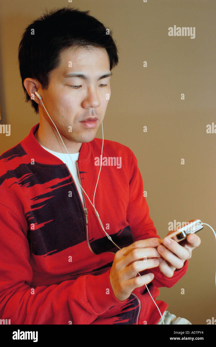 Porträt-Young "Asiatischen Mann" anhören von Musik auf einer tragbaren persönlichen Stereo-Musik "MP3 Player" 'I pod" Stockfoto