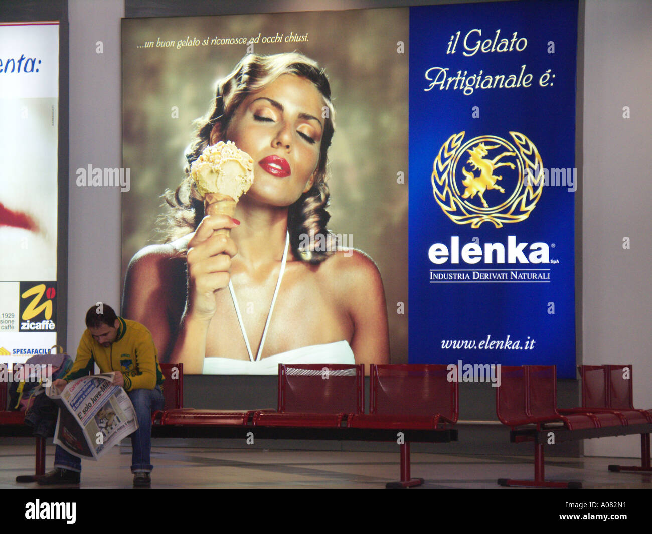 Mann liest Zeitung vor großes Plakat Werbung Frau mit großen Eis Flughafen Palermo Sizilien Italien Stockfoto