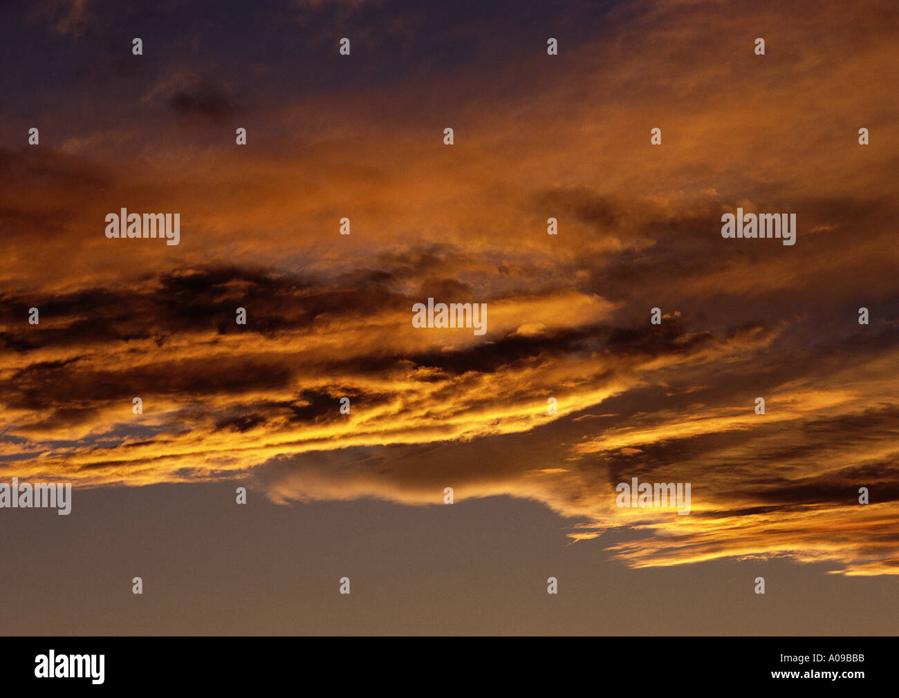 Eine dramatische glühende Skyscape bei Sonnenuntergang, gekennzeichnet durch dicke orange Wolkenfetzen gemacht durch die Reflektion der Sonne s brillant Stockfoto