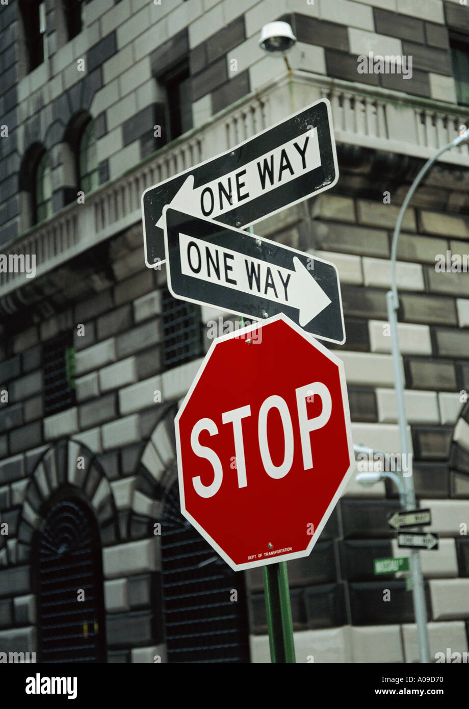 Zwei ONE-WAY-Zeichen über ein STOP-Schild in einem städtischen Umfeld Stockfoto