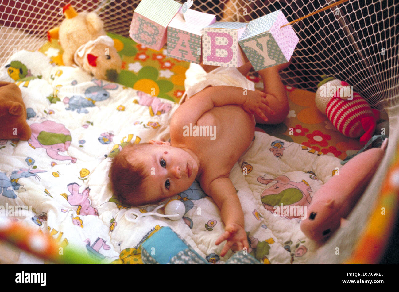 Baby im Laufstall mit Spielzeug Stockfoto