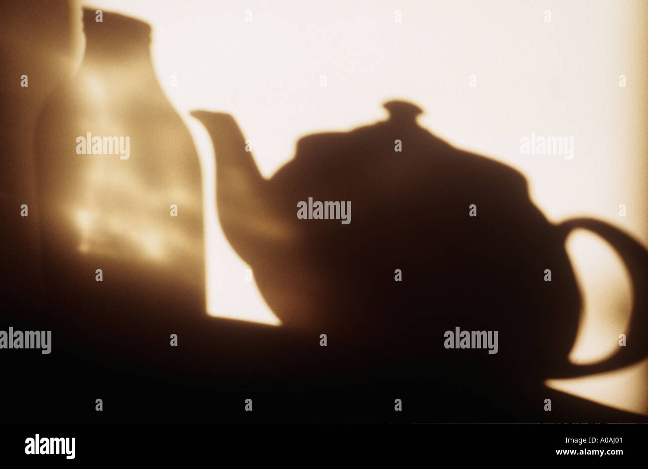 Schatten an der Wand der Teekanne und Milch Flasche auf einem Tisch mit Reflexen aus der Flasche Glas stehend Stockfoto