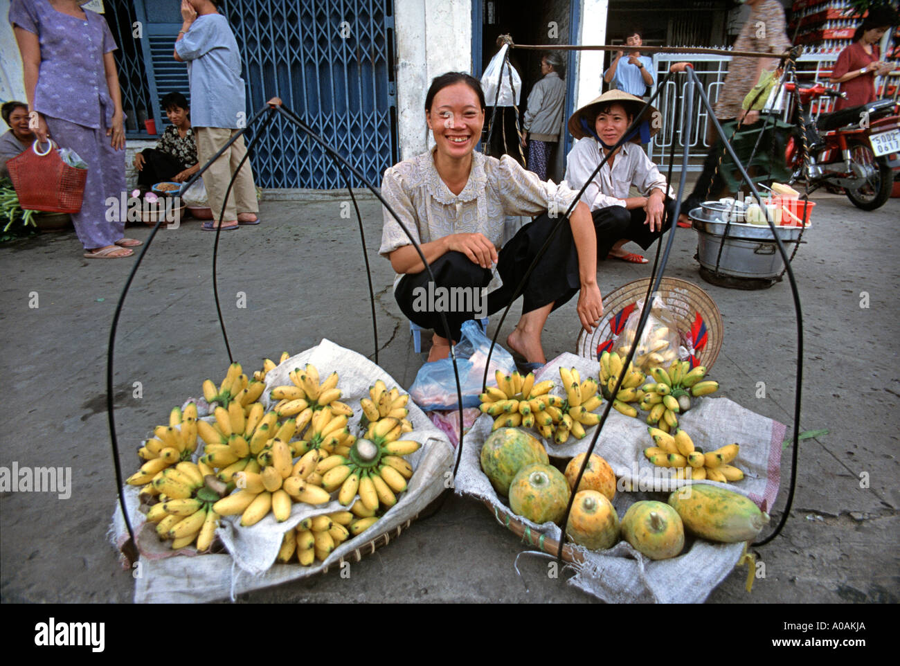 Freundlichen vietnamesische Obstverkäufer sitzt auf einem Bürgersteig neben ihr waren Ho Chi Minh Stadt Saigon Vietnam Stockfoto