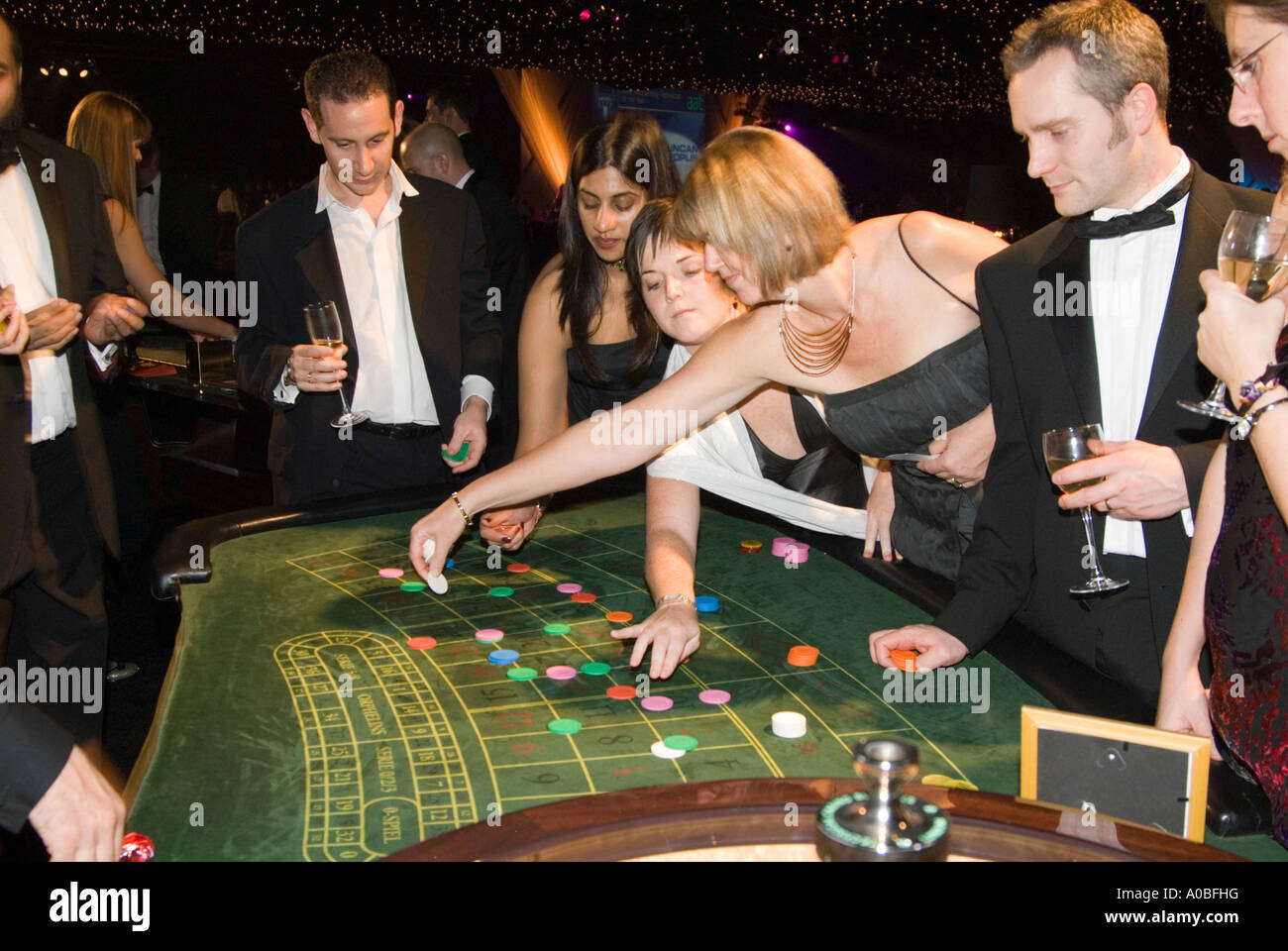 Menschen setzen ihre Chips auf dem grünen Filz von einem Roulette-Tisch im Rahmen einer Firmenveranstaltung England UK Stockfoto