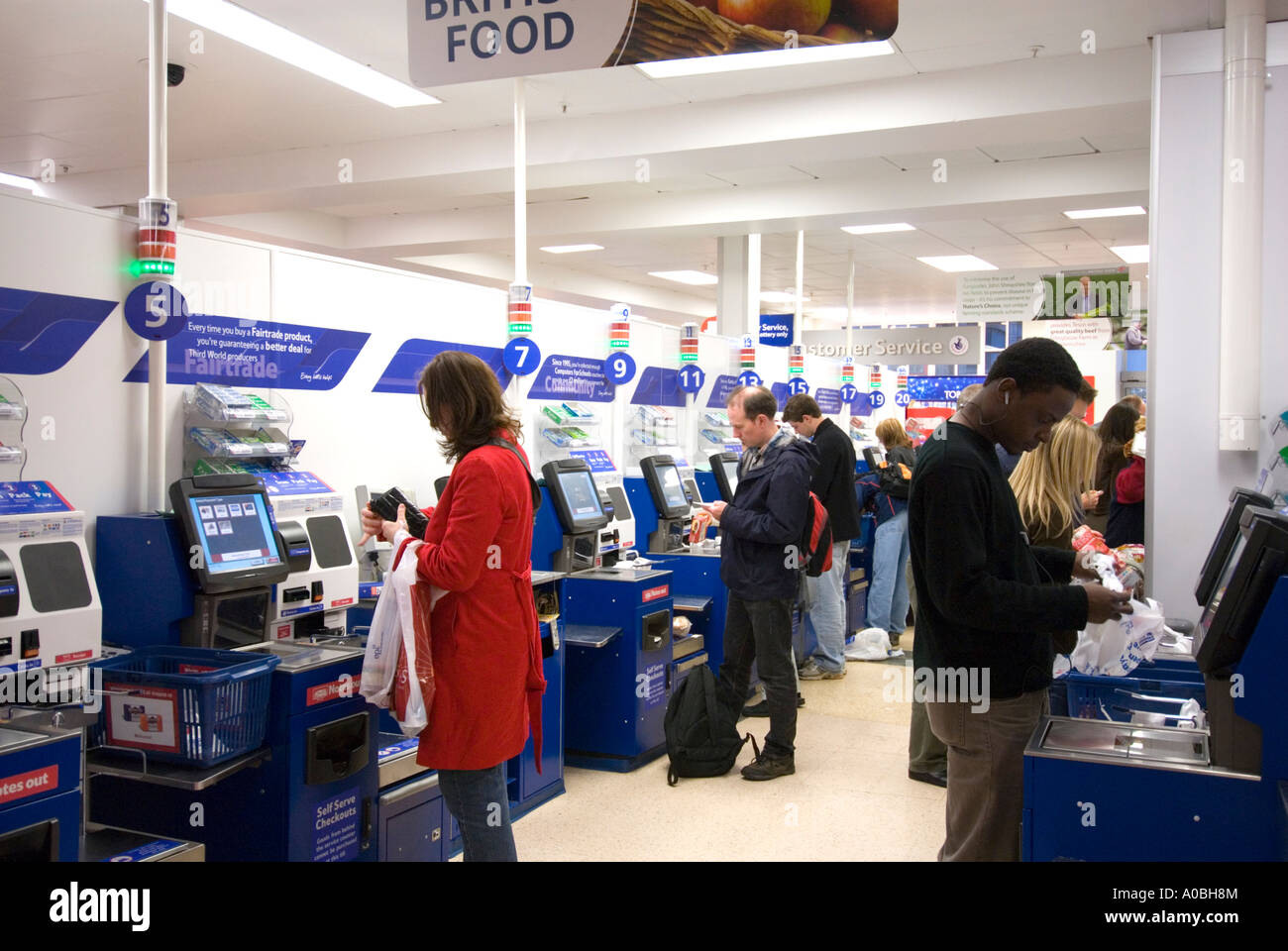 Kunden, die die SB-Kassen-Terminals bei Tesco, England UK Stockfoto