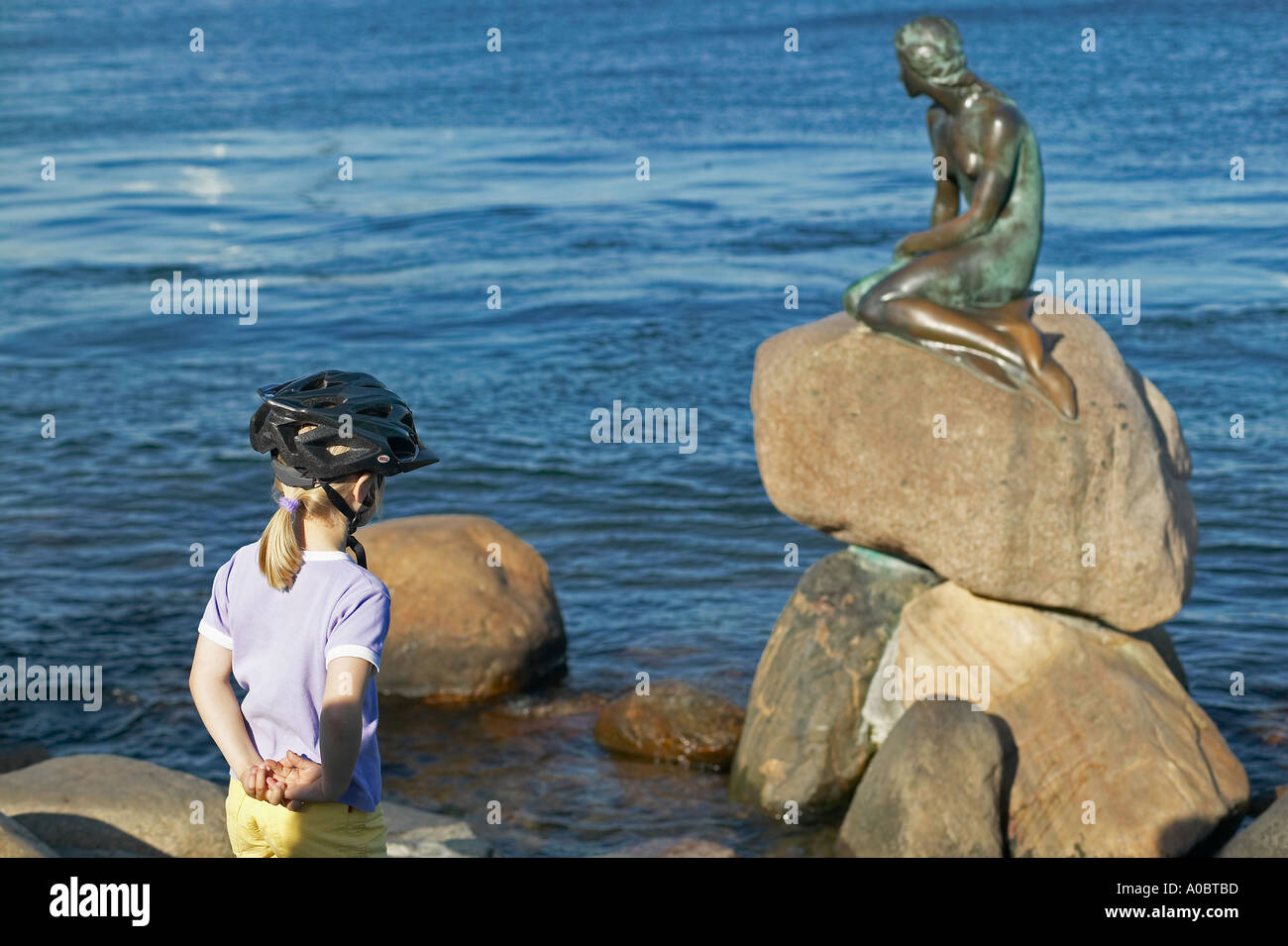 Kleines Mädchen mit Fahrradhelm beim Blick auf die kleine Meerjungfrau Statue, Kopenhagen, Dänemark, Europa Stockfoto