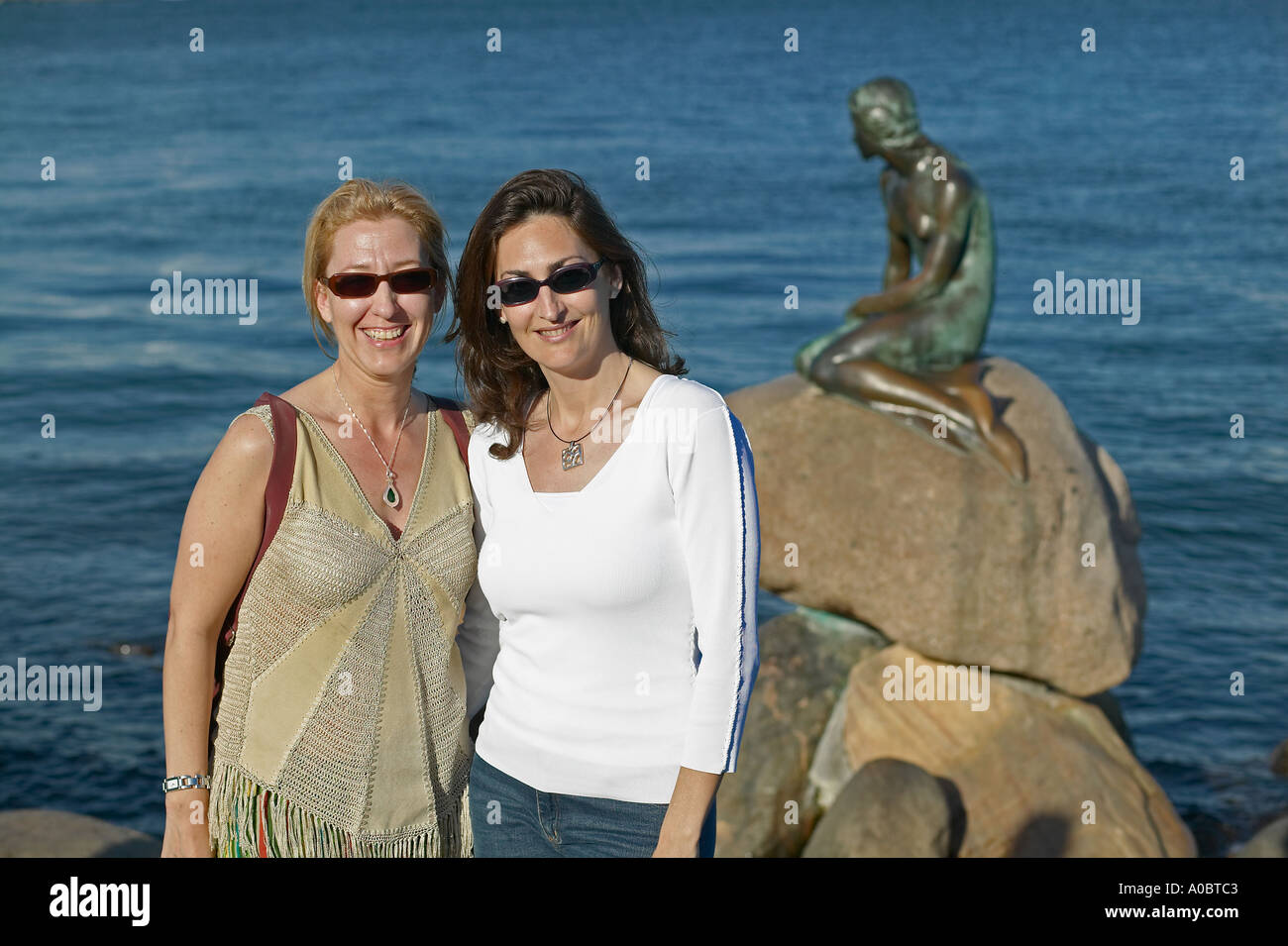 Zwei Spanische junge Frauen vor der Statue der Kleinen Meerjungfrau Posing, Kopenhagen, Dänemark, Europa Stockfoto
