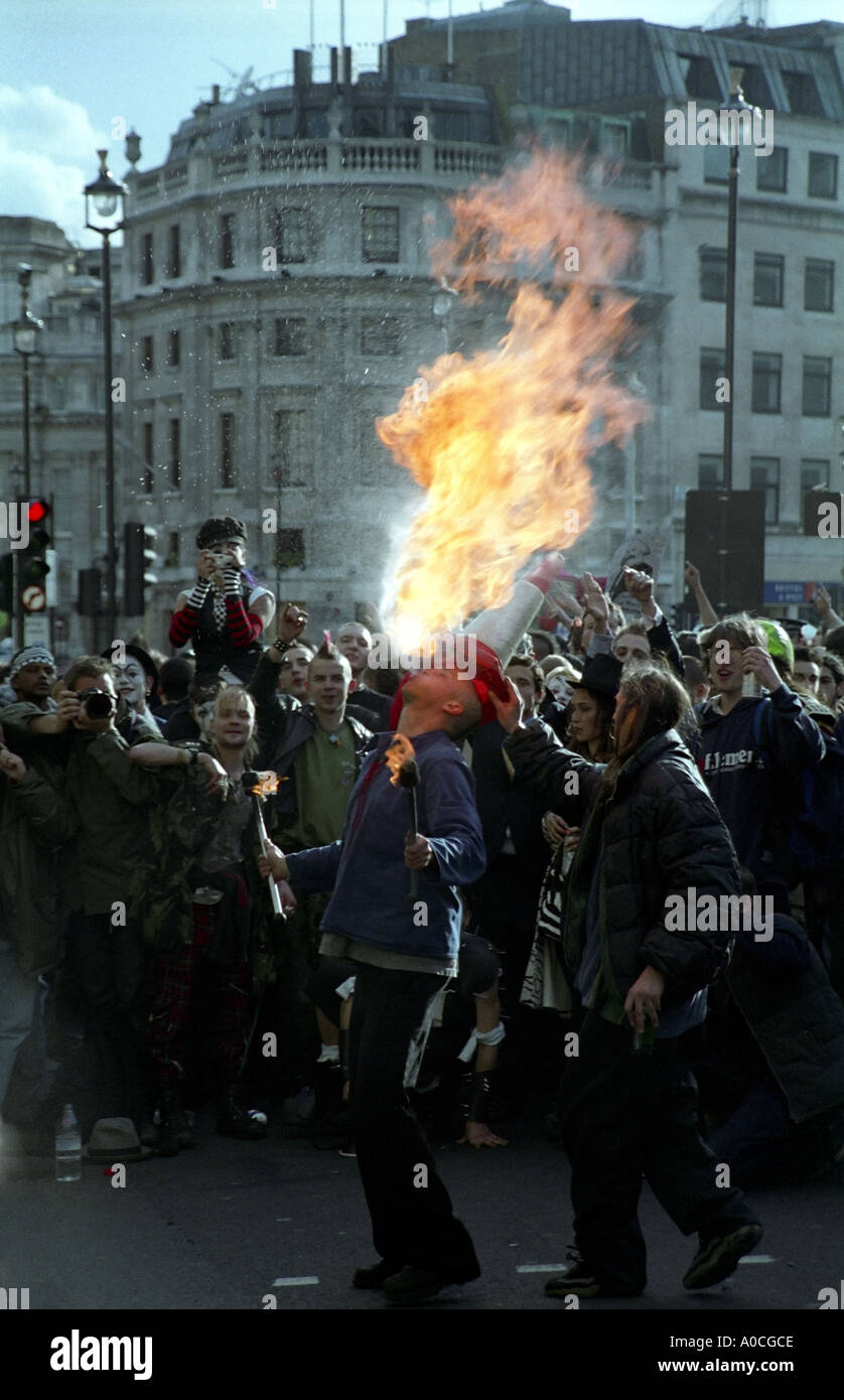 Ein Mann spuckt Feuer, während ein anderer Mann einen Kegel auf dem Kopf während der 2003 Maifeiertag Proteste in Trafalgar Square in London legt Stockfoto