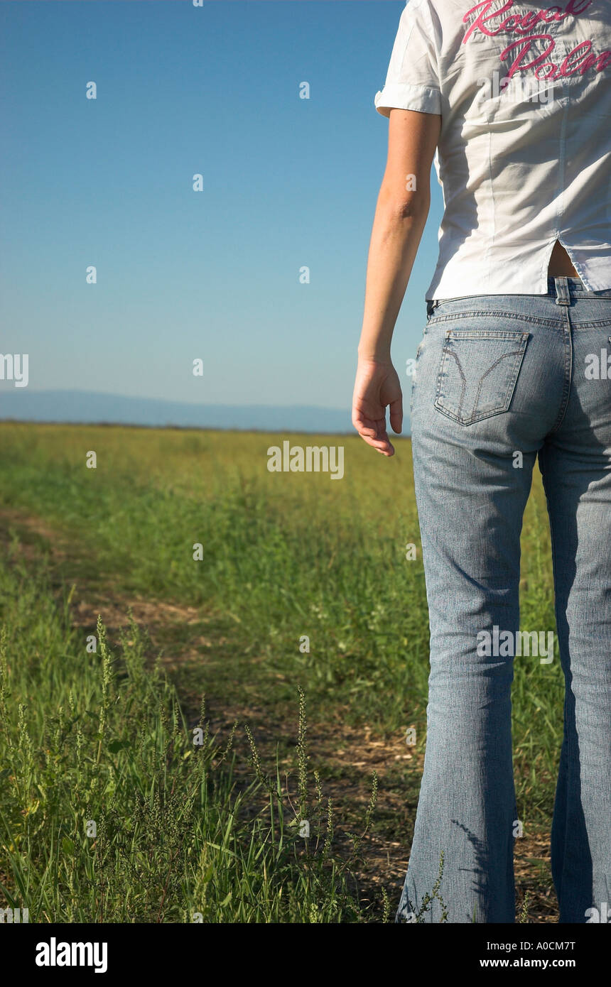 Junge Frau trägt Freizeitkleidung stehen im Feld Rückansicht Stockfoto