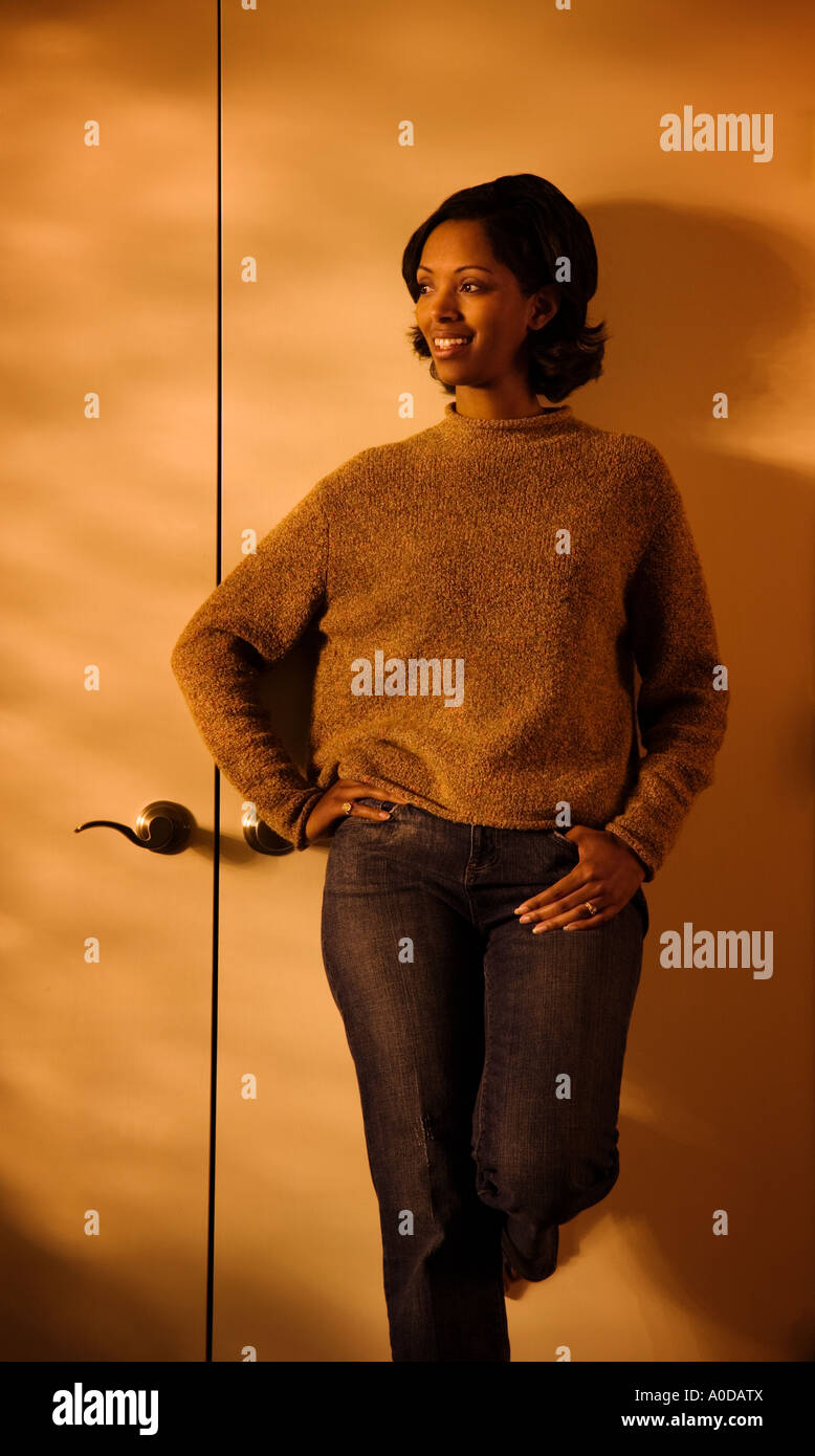 30 s afroamerikanische Frau in Freizeitkleidung lächelnd zurücklegt gegen eine Schranktür in ihrem Haus Stockfoto