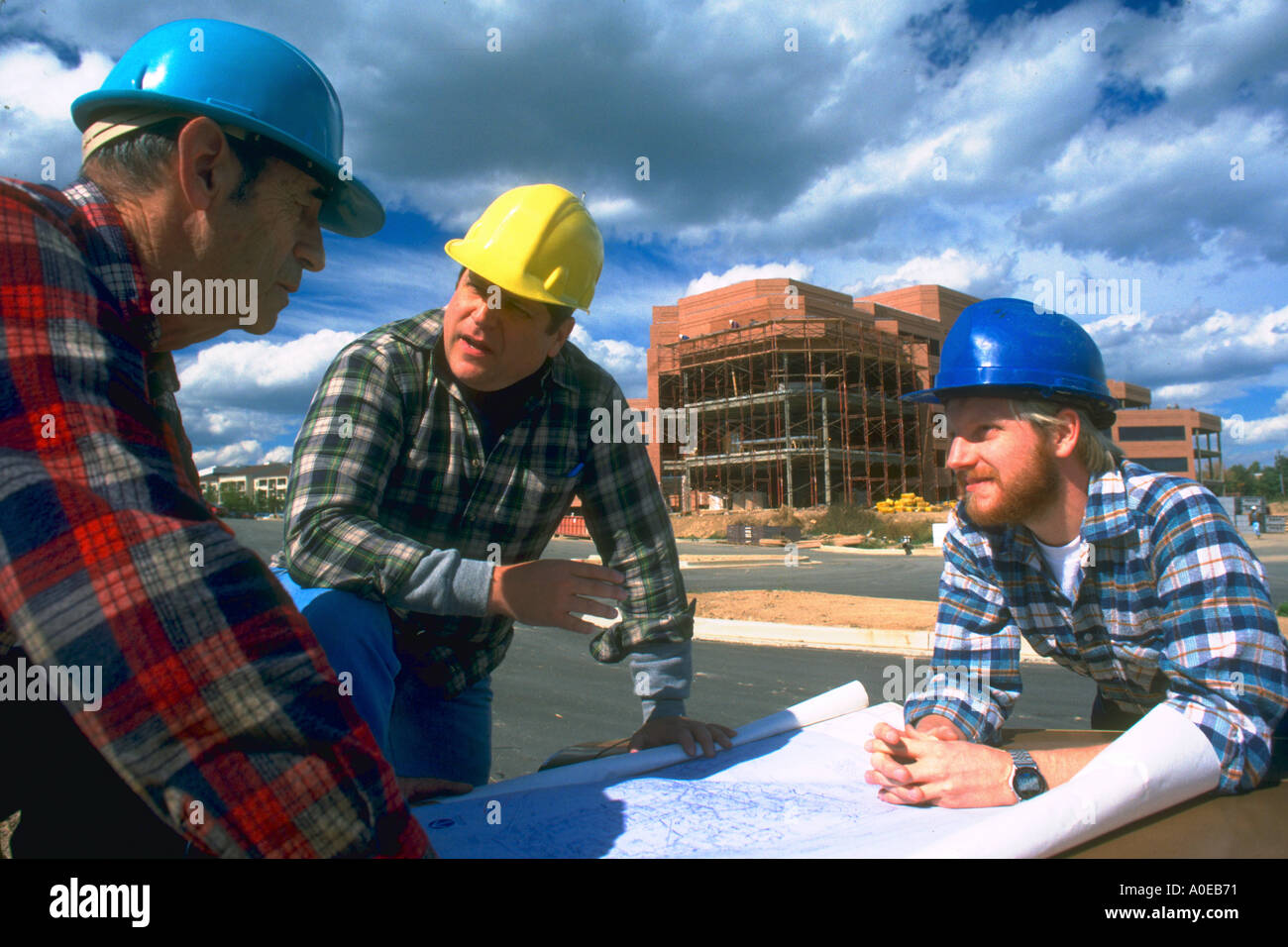 Zwei Bauarbeiter und ihrer Vorgesetzten besprechen Pläne für Bürogebäude Stockfoto