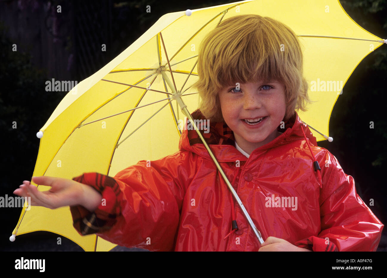 Junges Mädchen in Regenmantel mit Regenschirm Stockfoto