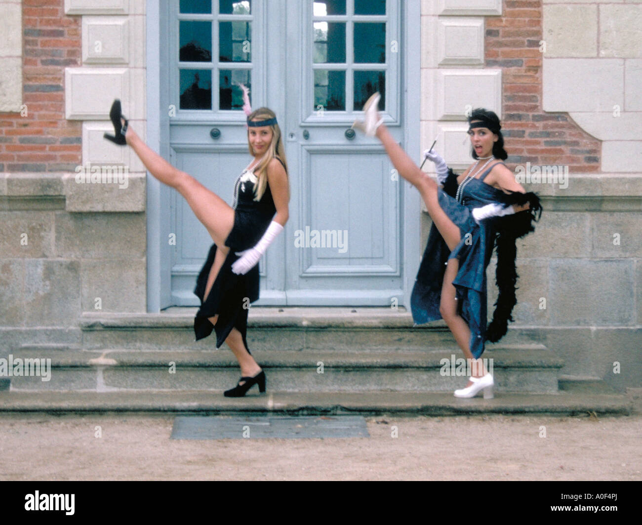 Zwei Mädchen in 1930er Jahren Flapper Kleider machen High Kicks in ein Tanzprogramm Stockfoto