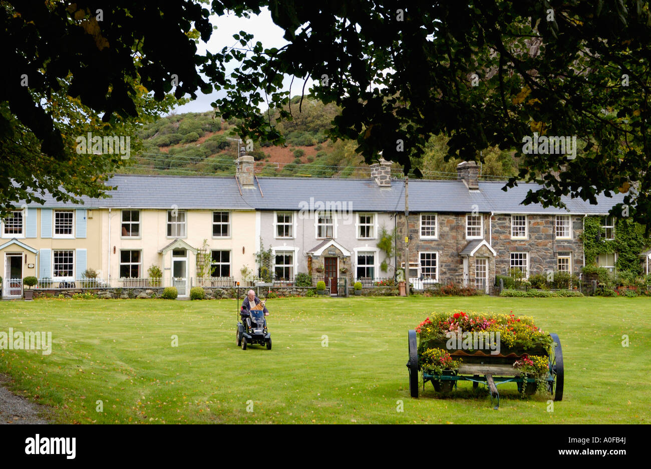 Reihe von traditionellen terrassenförmig angelegten Bungalows Beddgelert Gwynedd North Wales UK Mensch und Hund motorisierten Rollstuhl Stockfoto