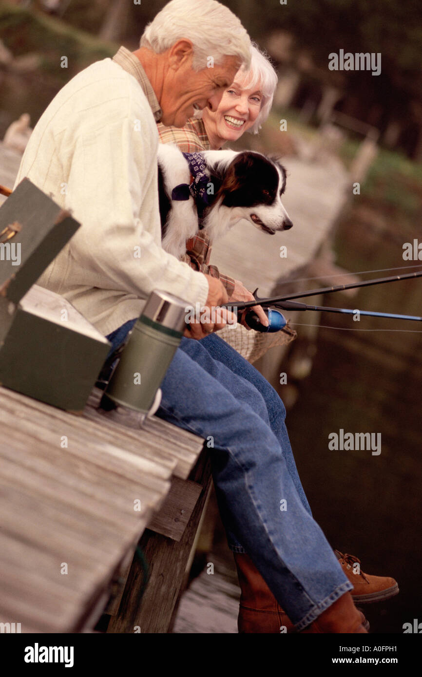 Seitenprofil ein älteres paar Angeln auf einem Pier mit ihrem Hund Stockfoto