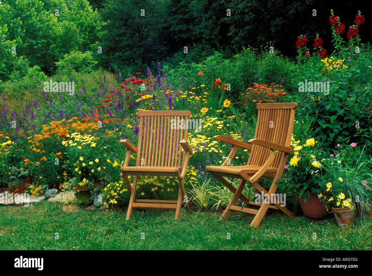 Zwei hölzerne Stühle begrüßen uns zur Zeit in einer bunten Land Blumengarten Midwest USA teilen Stockfoto
