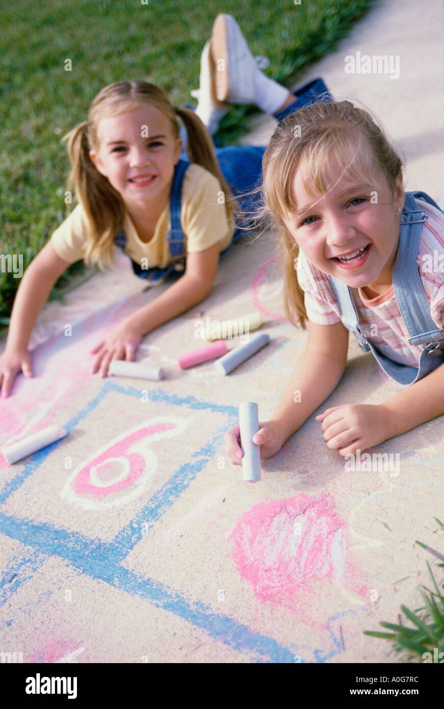 Porträt von zwei Mädchen auf dem Boden mit Kreide Stockfoto