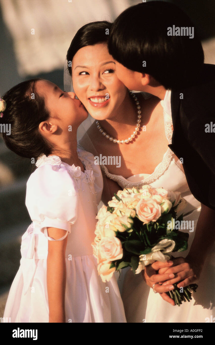 Blumenmädchen und Ringträger eine Braut küssen Stockfoto