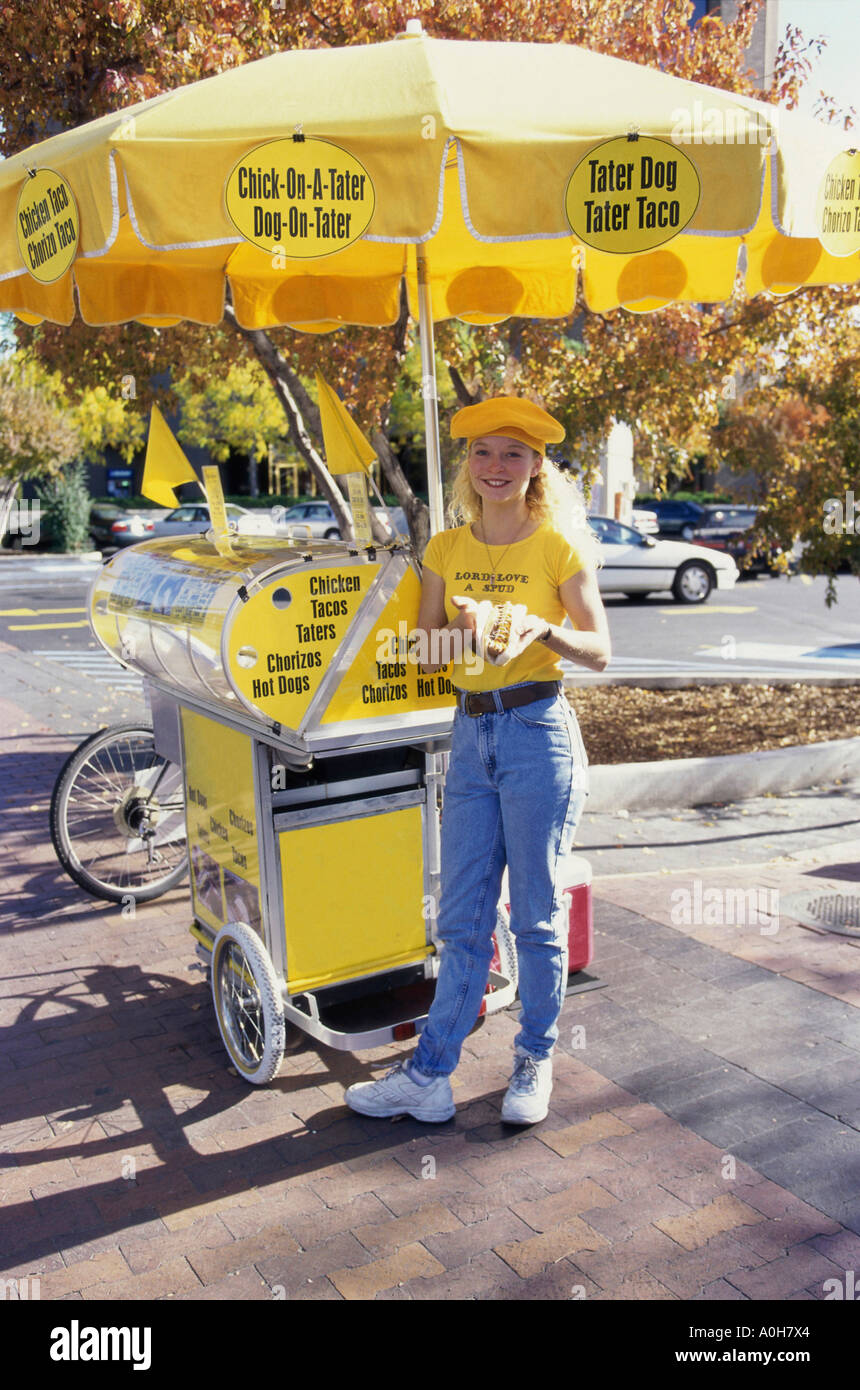 Porträt einer jungen Frau steht auf dem Bürgersteig, Verkauf von Hotdogs Stockfoto