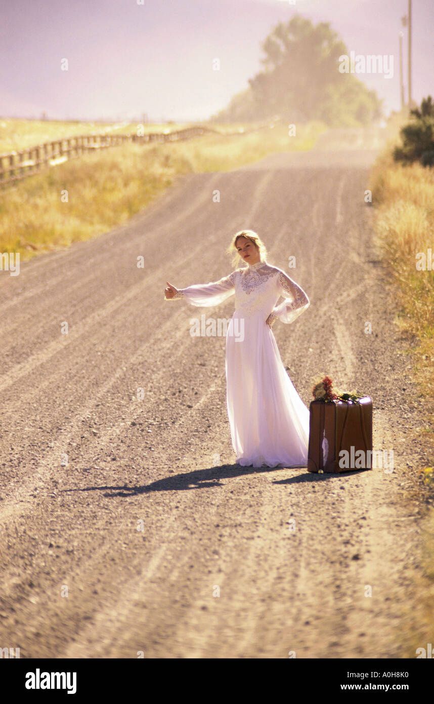 Junge Braut stehen an der Seite einer Straße mit einem Koffer Stockfoto